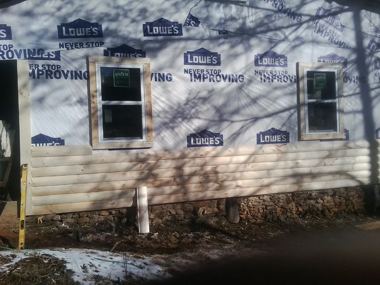 House wrap and new log siding going up on an exterior wall in Schuyler