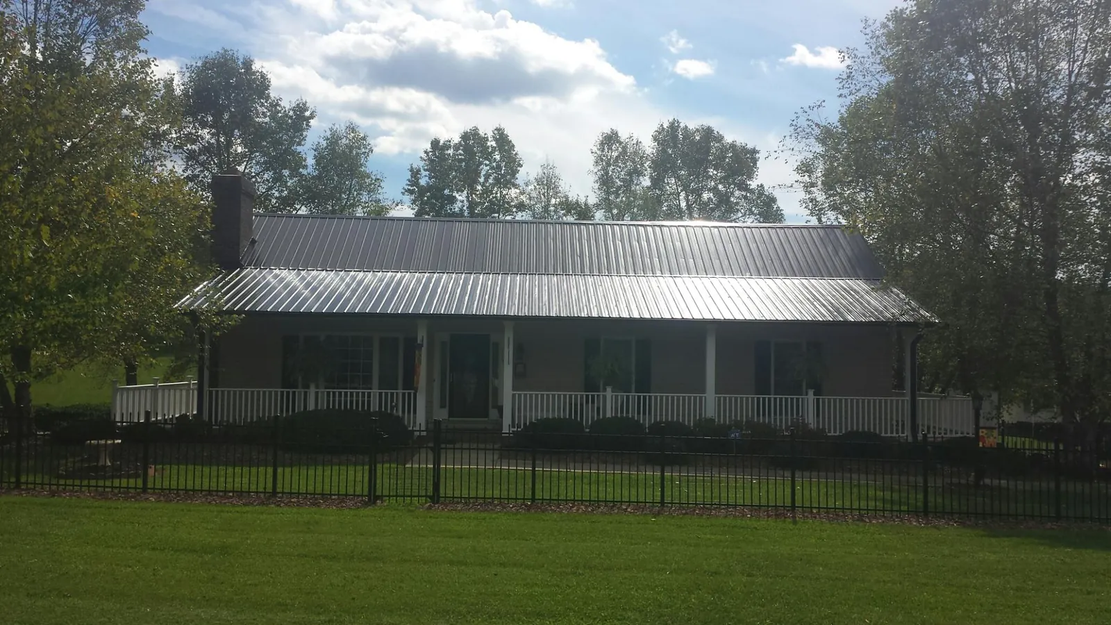 Gray metal roof on a brick ranch with a full width front porch — Gutter Guard Installation work by our crew in Schuyler